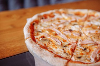 Sıcak bir kafede, ahşap bir masada taze pizza.