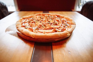 Sıcak bir kafede, ahşap bir masada taze pizza.