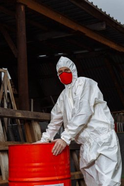 Korumalı takım elbiseli adam, kırmızı tıbbi maske ve lateks eldivenler. Şehrin harabelerinde Coronavirus COVID-19 salgını sırasında.