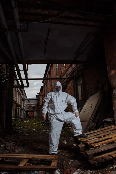 man in protective suit, grey medical mask and latex gloves during a coronavirus COVID-19 pandemic in the ruins of the city