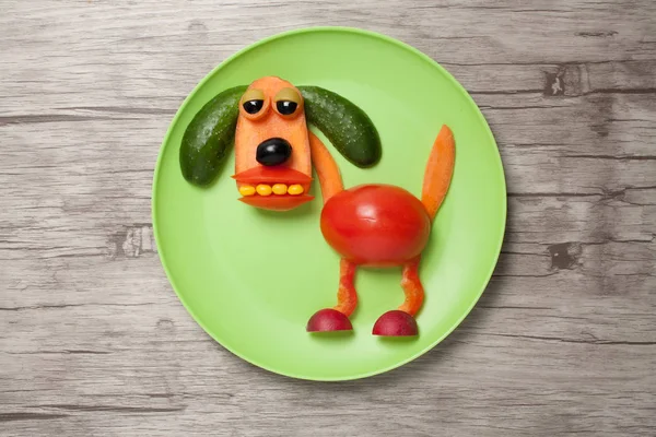 Zabawny pies z warzyw na talerz i drewniane tła — Zdjęcie stockowe