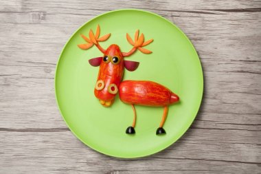 Yeşil plaka ve ahşap arka plan üzerinde sebze geyik