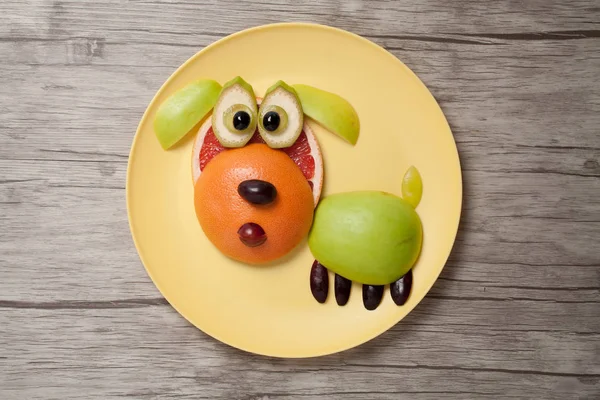 Funny ovoce pes na desku a dřevěné pozadí — Stock fotografie