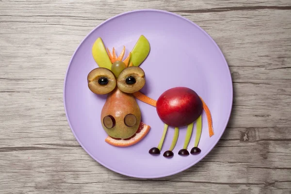 Fruit donkey on purple plate and wooden background — Stock Photo, Image