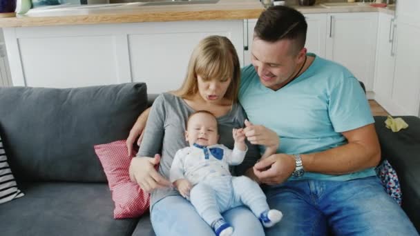 Una familia joven con un bebé en casa. Bebé travieso, papá acariciando su vientre. El dolor de barriga del niño — Vídeos de Stock