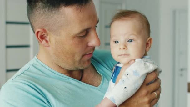 Feliz padre joven sosteniendo a su hijo dos meses, sonriendo. La alegría de la paternidad, la infancia feliz — Vídeos de Stock