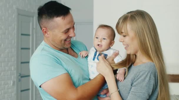 Jovens pais brincando com seu filho dois meses. Família feliz e conforto em casa — Vídeo de Stock