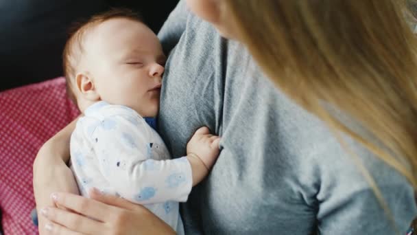 El bebé duerme dulcemente en los brazos de su madre. Vista trasera sobre el hombro — Vídeo de stock