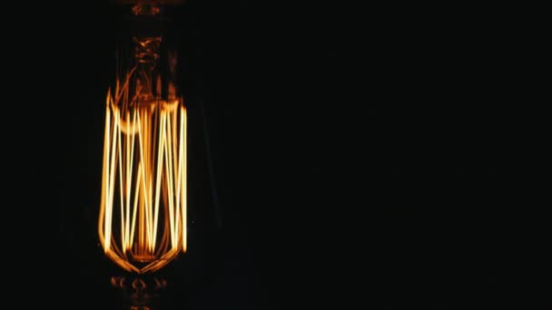Oblong Vintage lamp Edison. Slowly turn on a black background. Near the free space for titles — Stock Video
