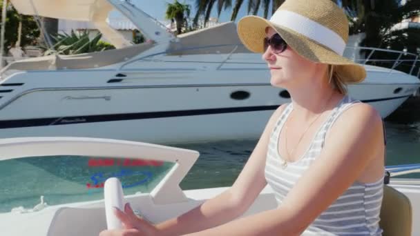 Young woman tourist with sunglasses sitting at the controls of a small boat. Sails Empuriarava channel in Spain. Concept: vacation in Europe and Spain — Stockvideo
