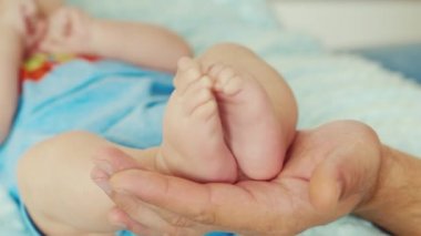 Yetişkin bir erkek el küçük bir bebek ayakları tutan. Kavram - bakım ve ebeveynlerin korunması ve mutlu çocukluk