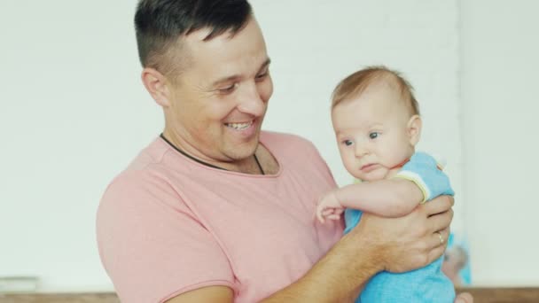 Boldog fiatal apa fiával a karjaiban, mosolyogva otthon — Stock videók