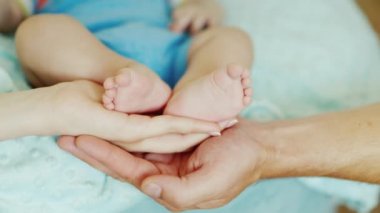 Avuç içi anne ve baba küçük ayaklar bebek ayakları tutmak. Velayet ve ebeveynlerin bakımı, mutlu ve sağlıklı bir aile