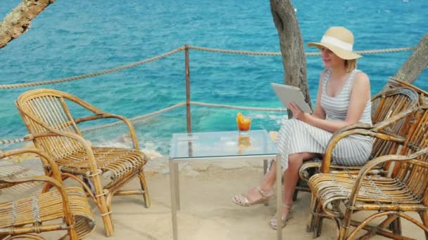 Vrouw toeristische spreekt met de tablet, altijd-op verbinding. Videochat van unieke plek met uitzicht op de zee — Stockvideo