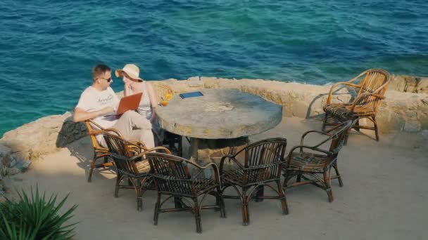 O casal no resort. O homem que trabalha com uma mulher de portátil senta-se perto. Vista superior — Vídeo de Stock