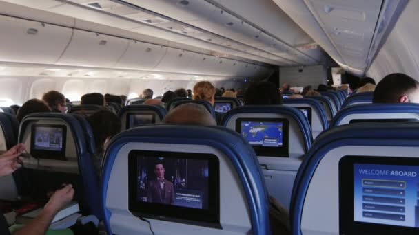 Nueva York, EE.UU. - OKTOBER 12, 2016: Viajes aéreos. Los pasajeros dentro de la cabina del avión, viendo videos y películas en la pantalla incorporada — Vídeo de stock