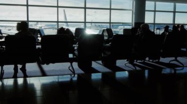 Siluetleri yolcu terminal havaalanında. Büyük pencere adlı bir uçuş kalktıktan bir yolcu uçağı yerde oturup...