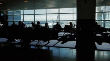 Yolcular bir bekleyen uçak uçuş otur. İnsanlar yürüyüş tarafından parlama siluetleri, gölgeler ve güneş pencereden bakın