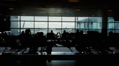 İzleme büyük Havaalanı terminal bir kadeh. siluetleri yolcu uçuşları için bekliyor. Pencerenin uçakları standı