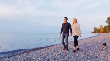 Gün batımında sahilde yürüyüş genç çok etnik gruptan oluşan bir çift. Asyalı erkek ve beyaz kadın