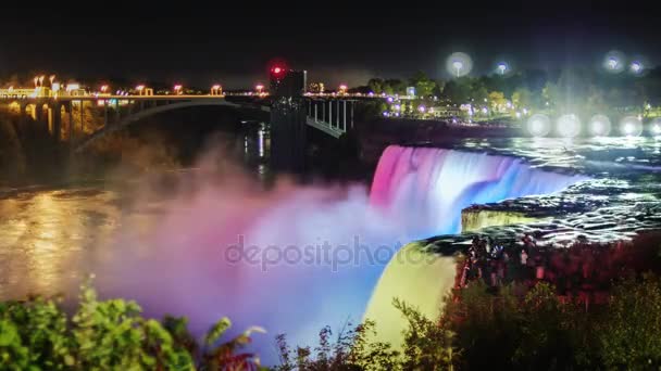 Niagara Falls in de nacht. De jets van vallende water zijn verlicht met gekleurde schijnwerpers. Prachtig prachtig gezicht - populair onder toeristen — Stockvideo