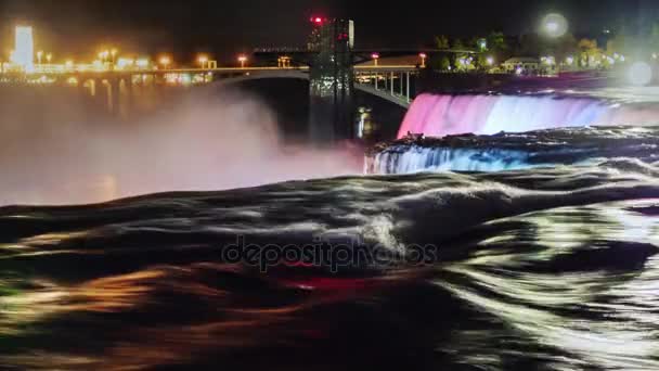 Niagara Falls w nocy. Strumienie spadającej wody są podświetlane kolorowymi reflektorami. Przepływ wody na ciemny pierwszego planu — Wideo stockowe