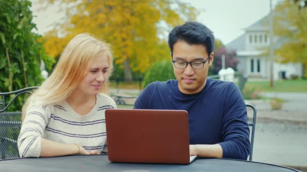 Junge Freunde - asiatische Mann und kaukasische Frau, die Video auf dem Laptop. Lächeln — Stockvideo