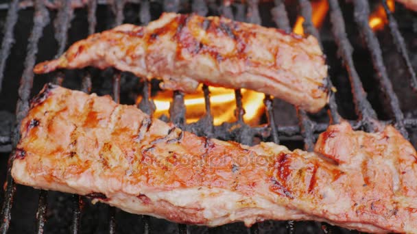 Trozos jugosos de costillas de cerdo asadas en una parrilla de barbacoa — Vídeo de stock