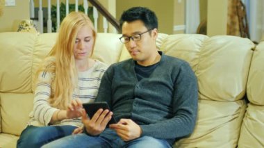 Arkadaşlar - Kore erkek ve beyaz kadın evde istirahat. Bir tablet, iyi vakit keyfini çıkarın.