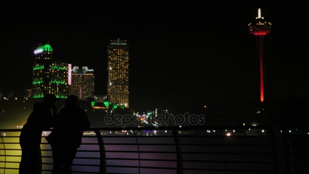 Man en vrouw bewonderen van de stad van de nacht. Let op de wolkenkrabbers, achteraanzicht, silhouetten. — Stockvideo