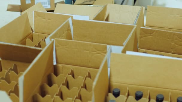 Упаковка пляшки з алкоголем. Робота кладе пляшку вина в картонні коробки — стокове відео