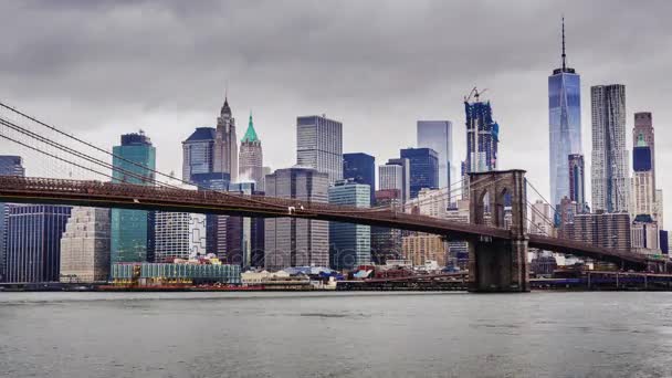 Vídeo 4K de Manhattan e Brooklyn Bridge, Nova Iorque. Nuvens rápidas flutuam sobre os arranha-céus, tempo nublado, tráfego pesado no rio — Vídeo de Stock