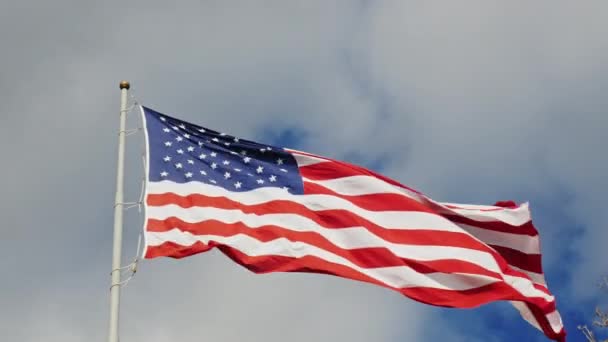 Большой флаг США на фоне серого неба, красиво освещенного солнцем — стоковое видео