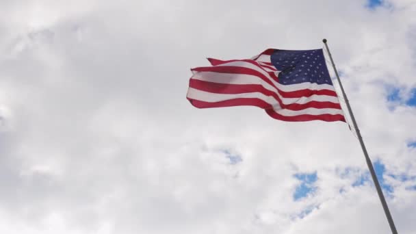 Duże nas flagi na tle szare niebo, pięknie oświetlone przez słońce — Wideo stockowe