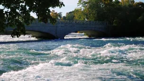 Puente sobre el río Niágara hasta la cascada. Río vibrante que fluye por debajo. Un lugar popular entre los turistas — Vídeo de stock
