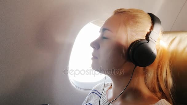 Young woman enjoys the flight, listening to music — Stock Video