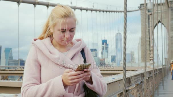 Turista joven en un abrigo rosa utiliza un teléfono inteligente . — Vídeos de Stock