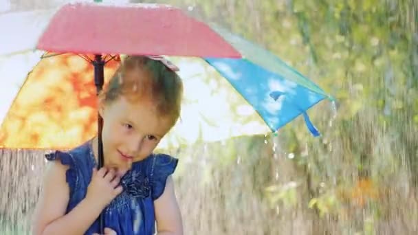 Grappig meisje verstopt onder een paraplu tegen de regen. Warme zomerregen — Stockvideo
