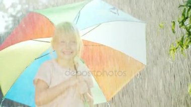 Kaygısız kız 5 yıl yaz yağmuru sevinir. renkli bir şemsiye altında duran.
