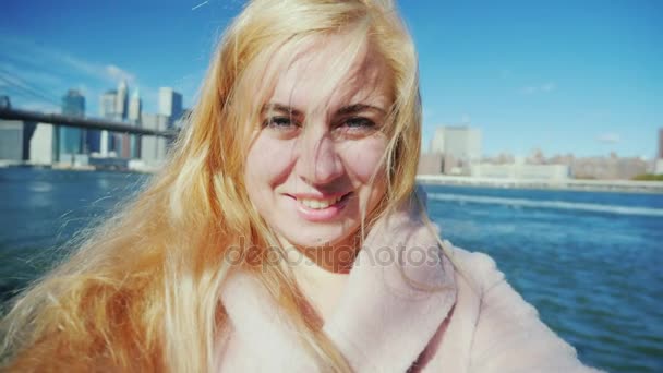 Ung attraktiv kvinna skjuter sig själv i videon på bakgrund av Brooklyn Bridge och Manhattan. — Stockvideo