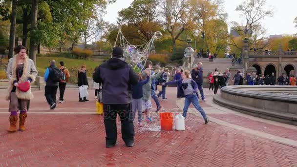 Нью-Йорк, США - OKT, 2016: Человек развлекает детей - лопаются пузыри в Центральном парке, Нью-Йорк — стоковое видео