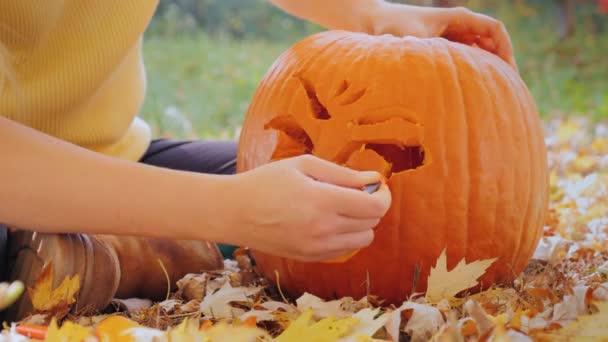 Las manos femeninas cortan la cara de la calabaza. Preparación para Halloween — Vídeos de Stock
