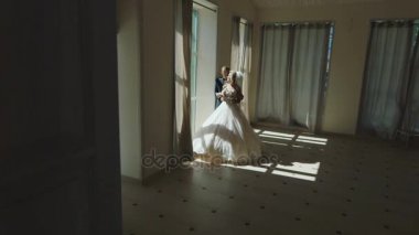 Gelin ve damat bir pencerede büyük salon ayakta zarif elbiseler