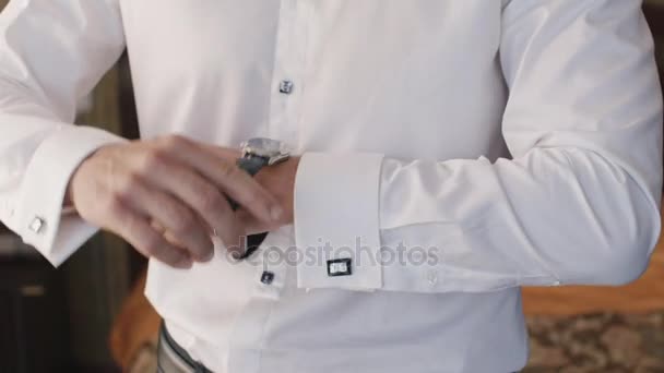 El hombre elegante en una camisa blanca lleva relojes de pulsera en la mano — Vídeo de stock