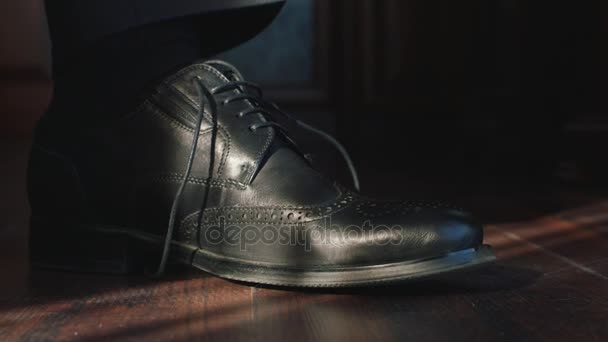 Человек завязывает шнурки на черных туфлях — стоковое видео