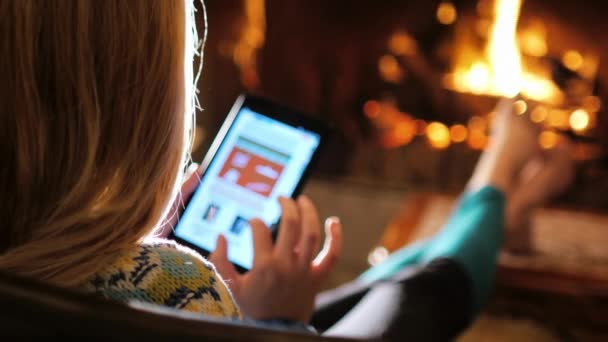 Femme bénéficie de la tablette dans une maison confortable près de la cheminée. Vue arrière 