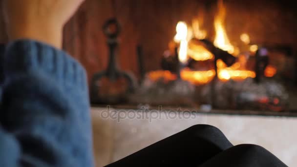 Hands with a cup of tea on a background of a burning fireplace. — Stock Video