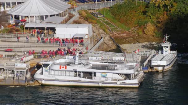 Niagara Falls, Ny - Oktober 21, 2016: Skupina turistů v červené pláště přichází na palubě výletní lodi. Chcete-li zobrazit Niagarské vodopády poblíž — Stock video