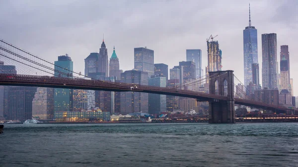 Manhattan y Brooklyn Bridge, Nueva York. Nubes rápidas flotan sobre los rascacielos, el clima nublado, el tráfico pesado en el río — Foto de Stock