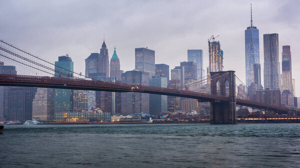Skyscrapers of Manhattan and Brooklyn Bridge, New York City. Fast clouds float over the skyscrapers, cloudy weather, heavy traffic on the river